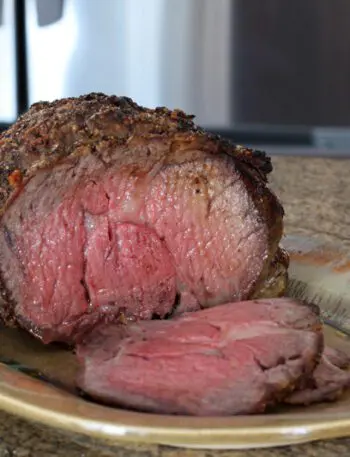 Ribeye roast on a serving tray with one slice cut out