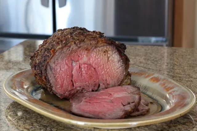 Ribeye roast on a serving tray with one slice cut out