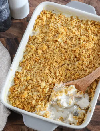 Serving the Ritz chicken casserole with a spoon and salt and pepper in the background.