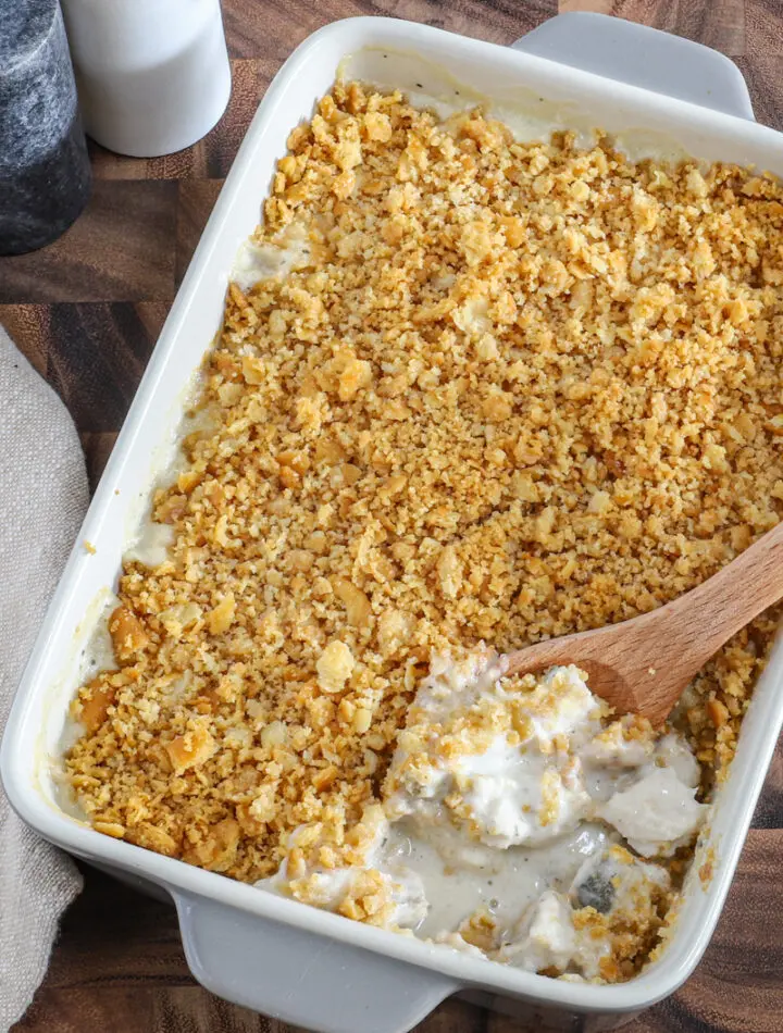 Serving the Ritz chicken casserole with a spoon and salt and pepper in the background.