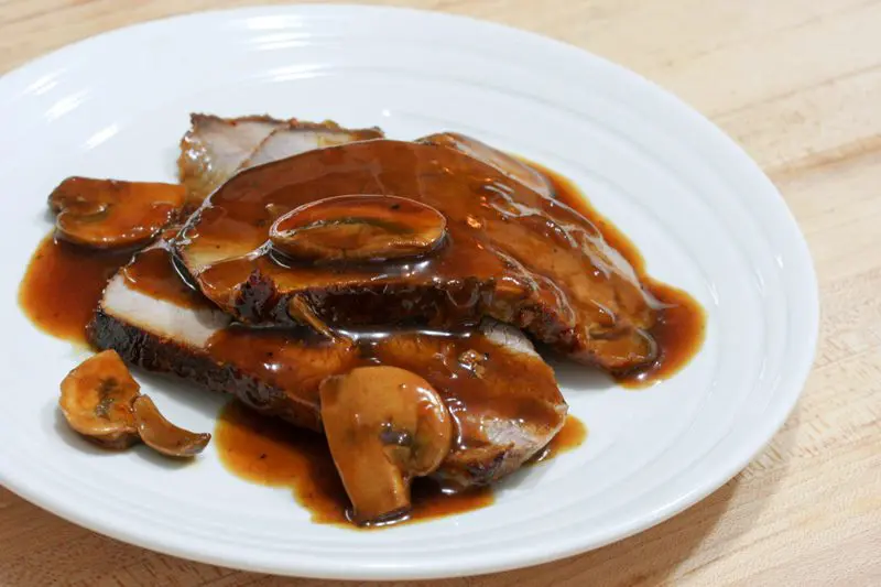 Closeup of roast beef slices with pan gravy and mushrooms