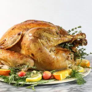 roast turkey on a platter with vegetables and herbs