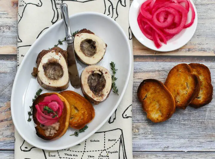 roasted bone marrow on an appetizer plate with pickled onions and crostini