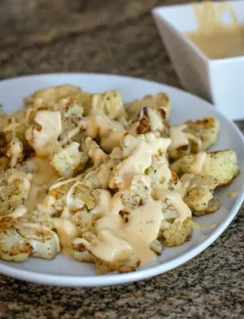 roasted cauliflower with cheddar cheese sauce on a serving platter