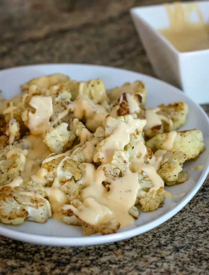 roasted cauliflower with cheddar cheese sauce on a serving platter