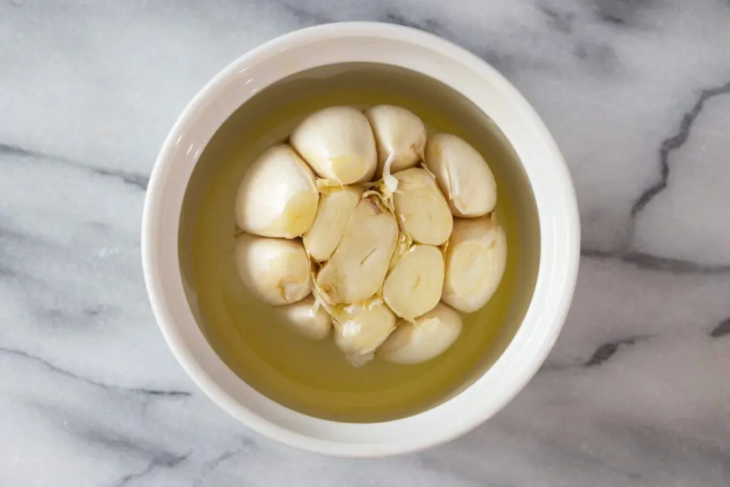 overhead photo of a bulb of garlic ready to roast in olive oil