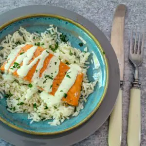 a salmon fillet on rice with basil mayonnaise and parsley garnish