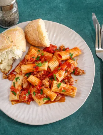 Overhead shot of a plate of rigatoni with a bright and flavorful sausage ragu made with Italian sausage, hand-crushed tomatoes, garlic, and onions.