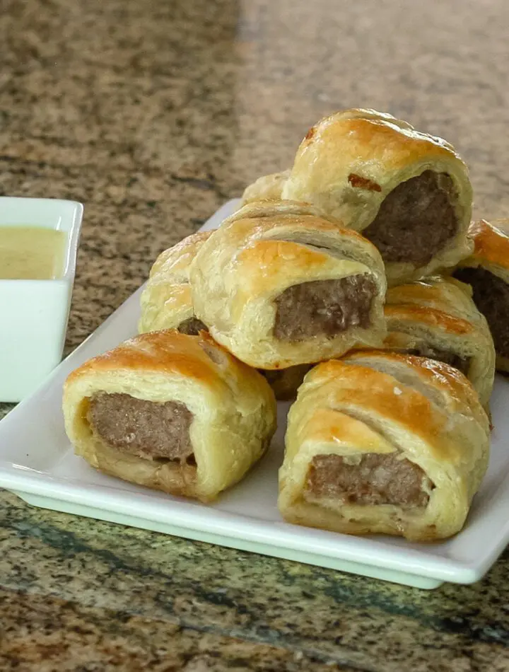 sausage rolls encased in puff pastry on a serving plate