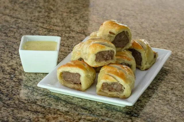 sausage rolls encased in puff pastry on a serving plate