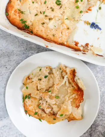 scalloped potatoes on a small plate beside the baking dish