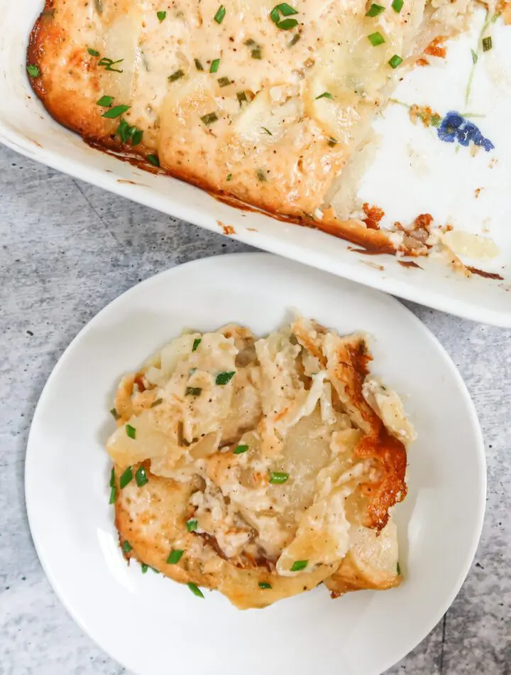 scalloped potatoes on a small plate beside the baking dish