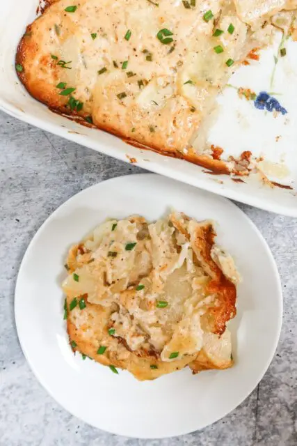 scalloped potatoes on a small plate beside the baking dish