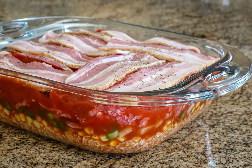 seven layer casserole ready for the oven with bacon on top