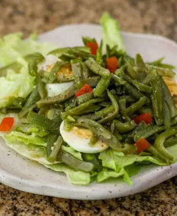 a simple green bean salad on a lettuce-lined plate