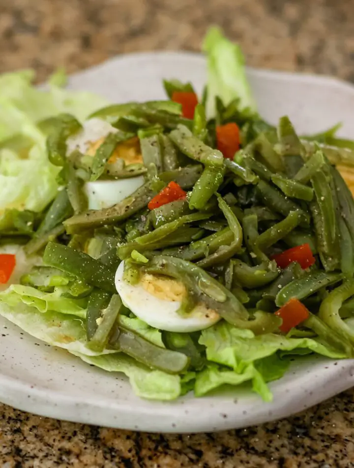 a simple green bean salad on a lettuce-lined plate