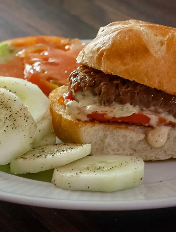 sliders with remoulade sauce on a plate with cucumbers and tomatoes