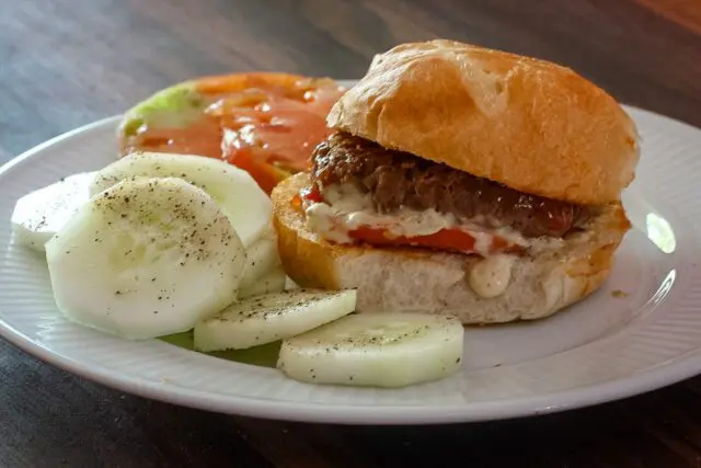 sliders with remoulade sauce on a plate with cucumbers and tomatoes