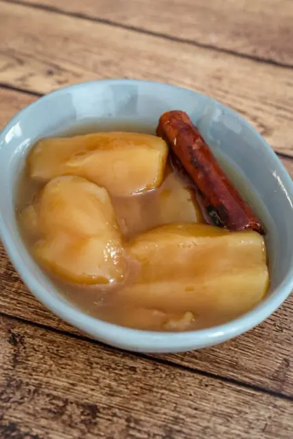 slow cooked apples in a small dish with a cinnamon stick