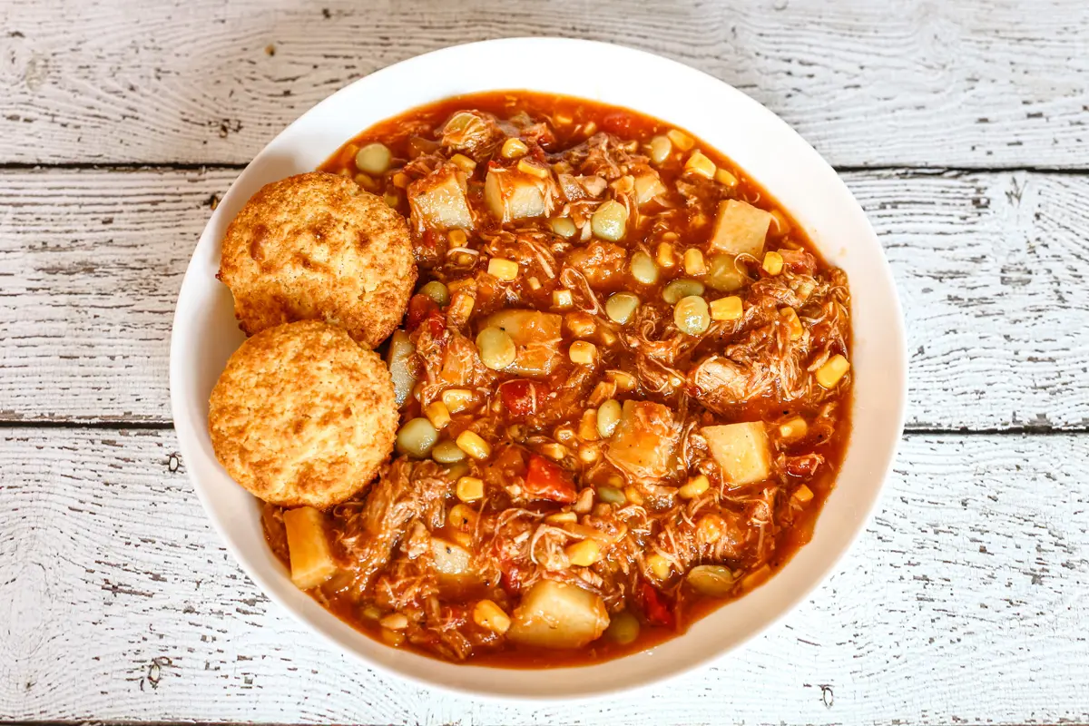 A bowl of rich and delicious Brunswick stew with corn muffins on the side.