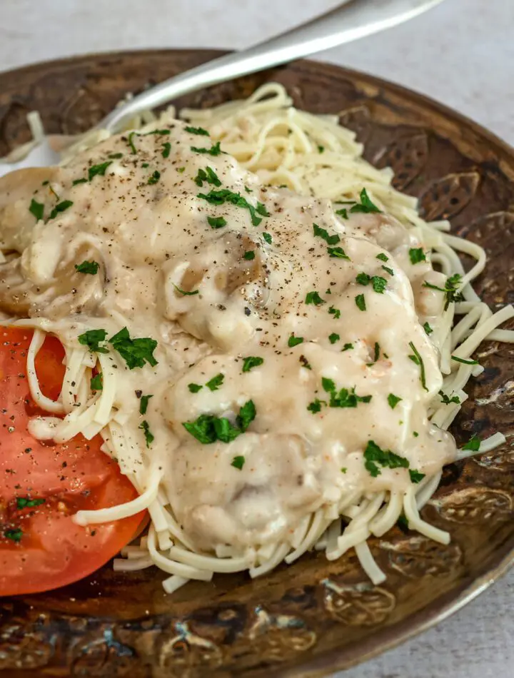 slow cooker chicken parisienne over pasta with sliced tomatoes on the side