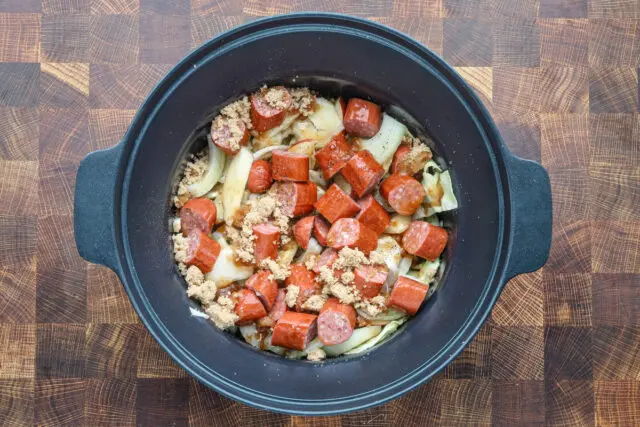 Slow cooker filled with sliced kielbasa, cabbage, apples, onions and flavorings, ready to cook on low.