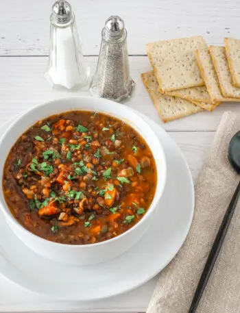 A bowl of slow cooker lentil soup with crackers.