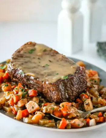 slow cooker pot roast and gravy surrounded by diced vegetables.