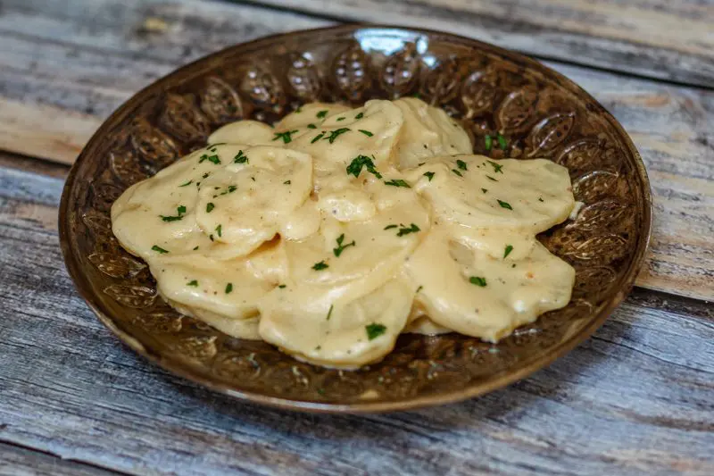 plate with crockpot scalloped potatoes with parsley garnish