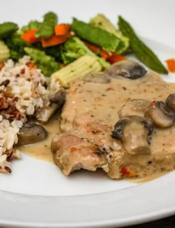 slow cooker pork chops on a plate with rice and vegetables