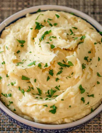 smoked cheddar mashed potatoes garnished with parsley in a serving bowl