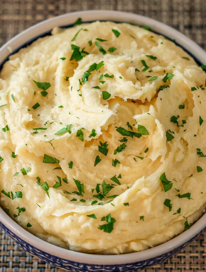 smoked cheddar mashed potatoes garnished with parsley in a serving bowl