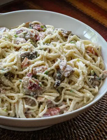 spaghetti with bacon and mushrooms in a serving bowl