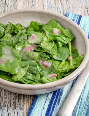 A serving of wilted spinach salad in a bowl