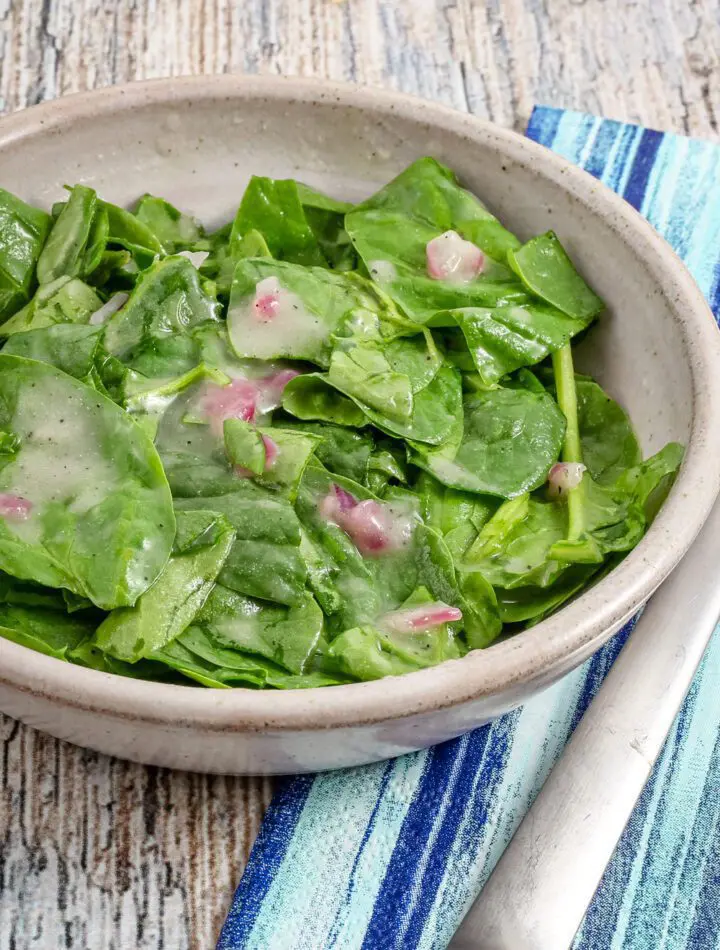 A serving of wilted spinach salad in a bowl