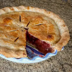 a baked strawberry rhubarb pie with 1 slice missing