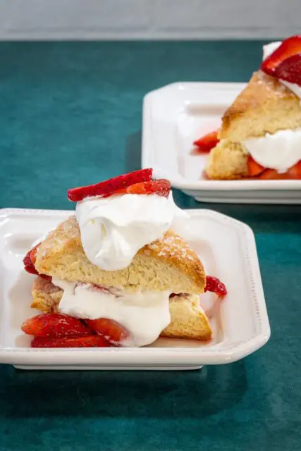 strawberry shortcakes on a plate: cream biscuits with strawberries and whipped cream