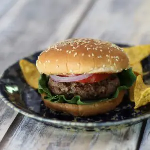 bacon and cheese stuffed burgers on a plate with chips