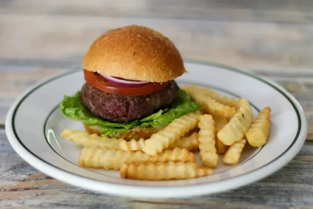 bacon and cheese stuffed burgers on a plate with fries