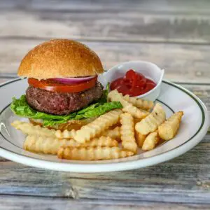 bacon and cheese stuffed burger on a plate with fries and ketchup