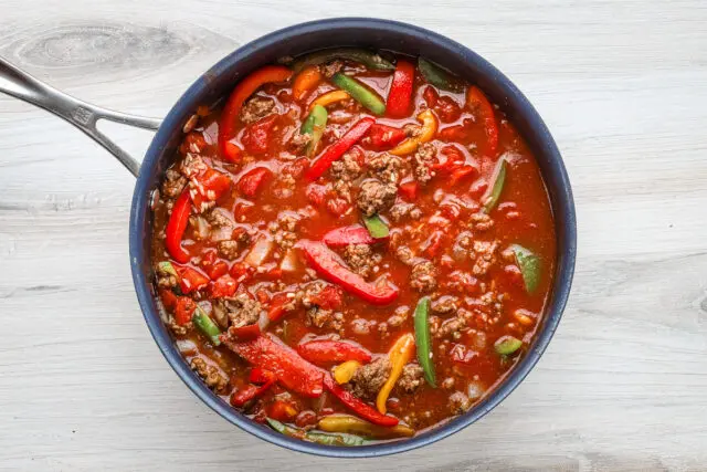 Adding rice, tomatoes, and tomato sauce to the one pot stuffed pepper casserole.