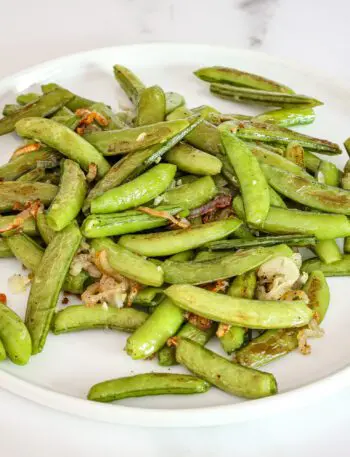 a plate of roasted sugar snap peas with shallots and garlic