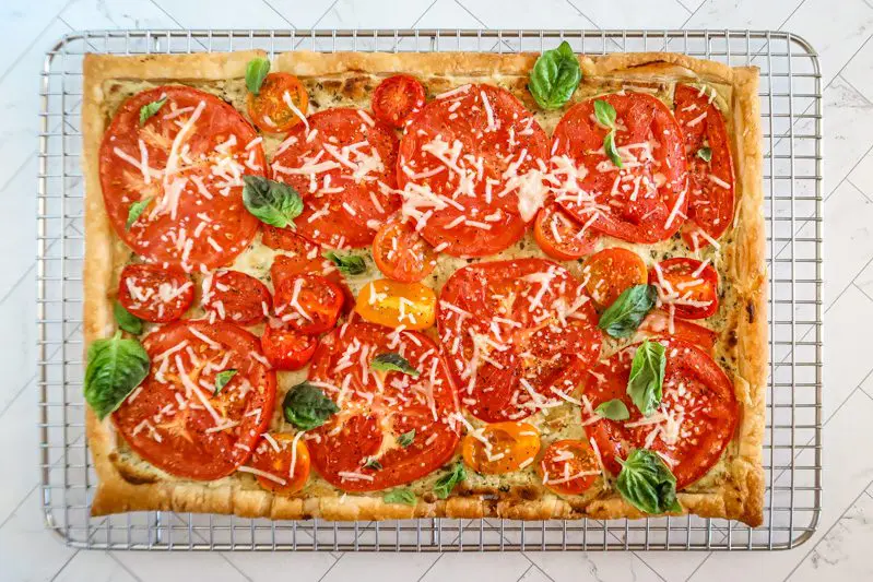 a baked tomato tart on a puff pastry and pesto-cream cheese base