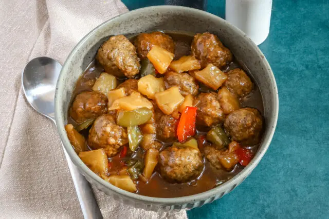 Slow cooker sweet and sour meatballs with pineapple and bell pepper chunks.