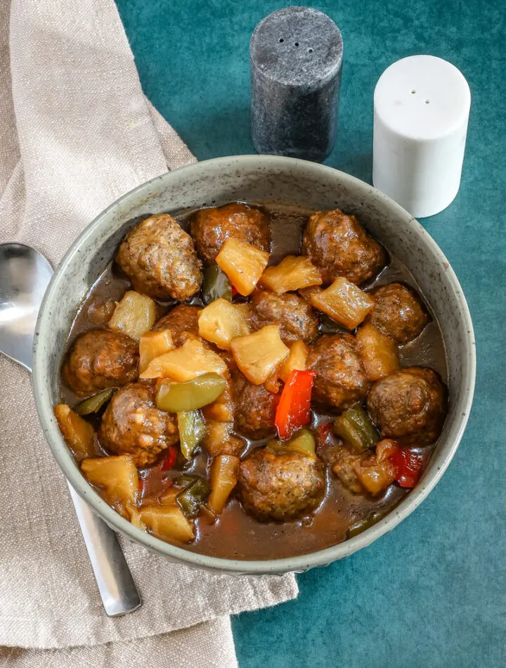 Slow cooker sweet and sour meatballs with bell pepper and pineapple chunks.