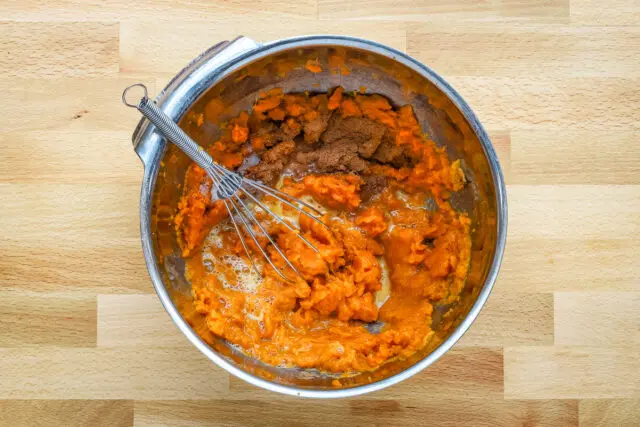 Mashing the sweet potatoes and combining them with the egg, spices, and brown sugar.