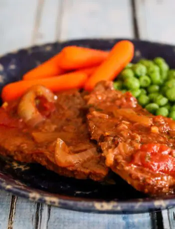 swiss steak on a plate with carrots and peas