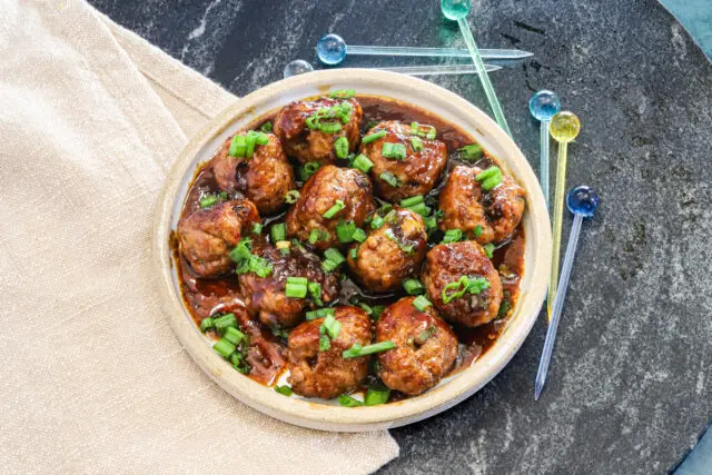 Teriyaki meatballs served as an appetizer with picks and a garnish of green onion tops.