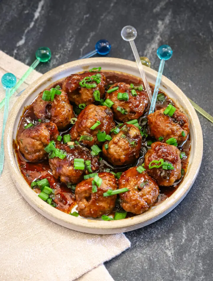 Teriyaki meatballs served as an appetizer with picks and a garnish of green onion tops.