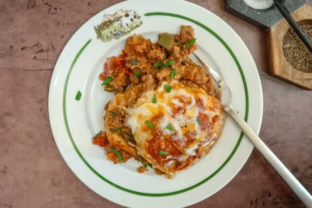 A serving of Tex-Mex beef and biscuit bake with garnish and a fork